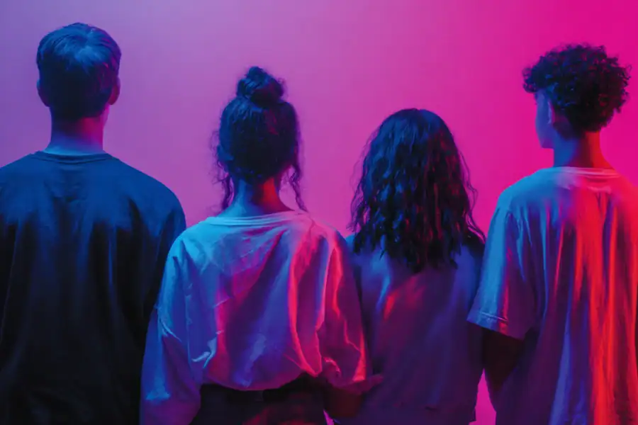Young diverse group of friends standing together under neon pink and blue lighting, modern youthful vibe.