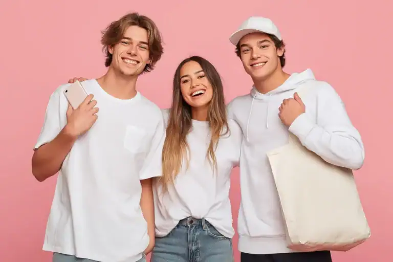 Young happy friends smiling, teenagers wearing casual white clothes, pink background.