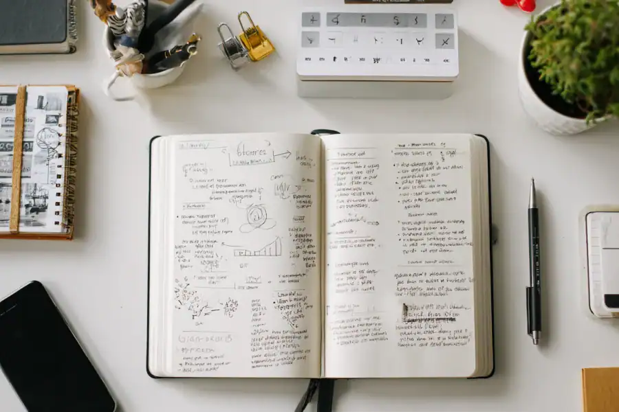 Open notebook with handwritten notes and diagrams on a clean workspace for studying or brainstorming.