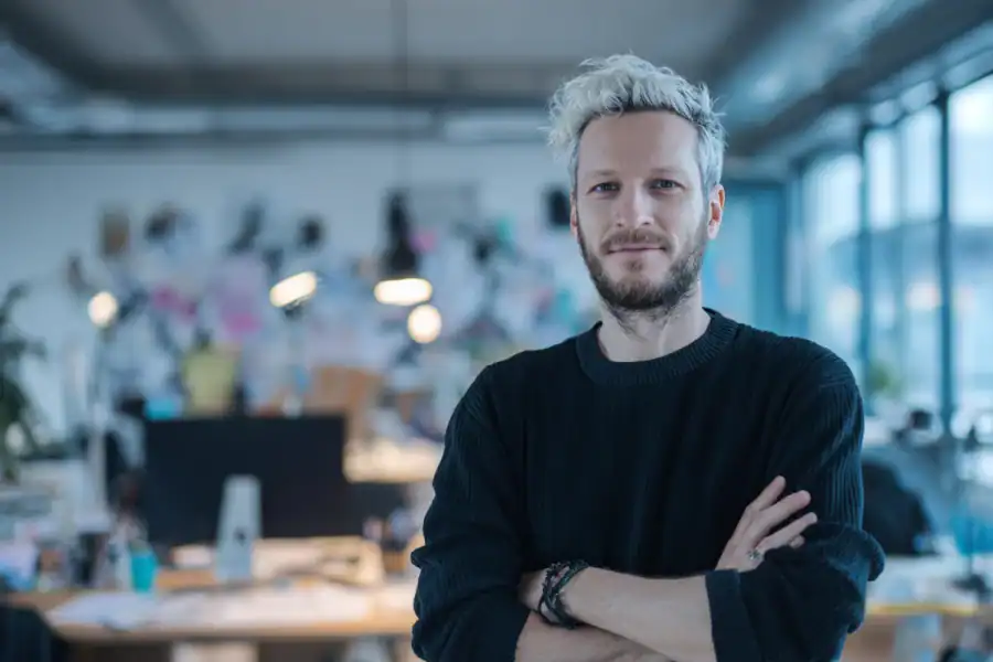 Innovative businessman in modern office with creative workspace background at Asmone.