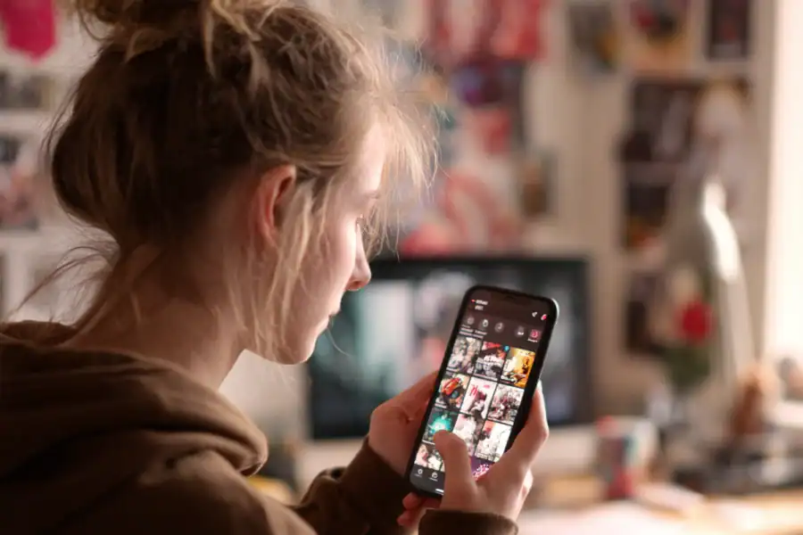 Young woman browsing Instagram on smartphone in creative workspace.